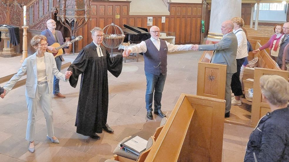 Ein Moment, der berührte: Stadtpastor Ralph Knöfler (3. von links) singt unter der Gitarrenbegleitung von Bernd van Geuns (hinten) gemeinsam mit den Anwesenden – darunter (von links) Kirchenvorstandsvorsitzende Anja Ihnen-Swoboda, der stellvertretende Superintendent Wolfgang Ritter und Bürgermeister Claus-Peter Horst – „We Shall Overcome“ . Foto: Dübbel