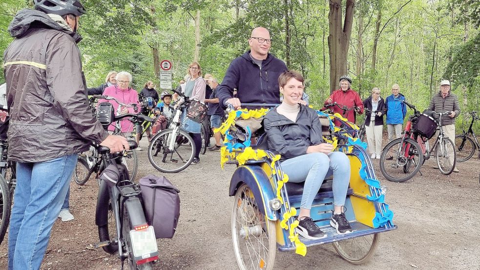 Mit einer Rikscha und begleitet von zahlreichen Gemeindemitgliedern auf ihren Fahrrädern kutschierte Kirchenvorsteher Meik Wilken Pastorin Lisa Koens. Foto: Dübbel