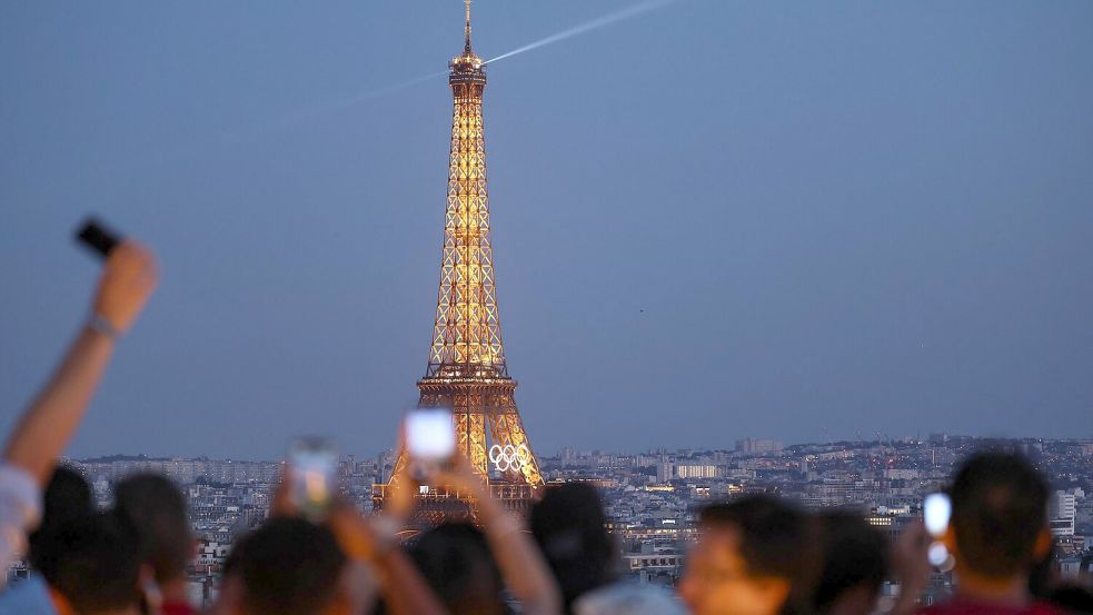 Paris im Sommer 2024 - besonders beliebt: Touristen fotografieren den Eiffelturm mit den Olympischen Ringen von der Terrasse des Triumphbogens. (Archivbild) Foto: Jan Woitas/dpa