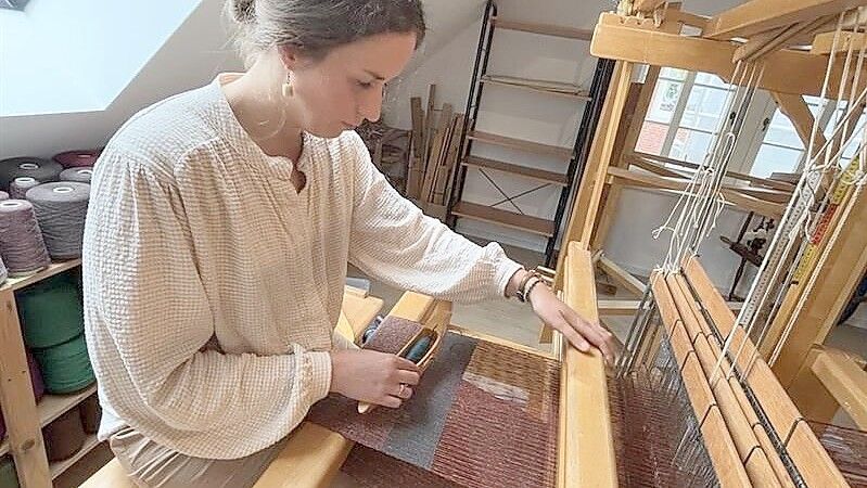 Linda Detering an einem der Webstühle in ihrer neuen Werkstatt. Reihe für Reihe wird das Garn mit dem Schiffchen zu einem Stoff gewebt. Foto: Susanne Ullrich