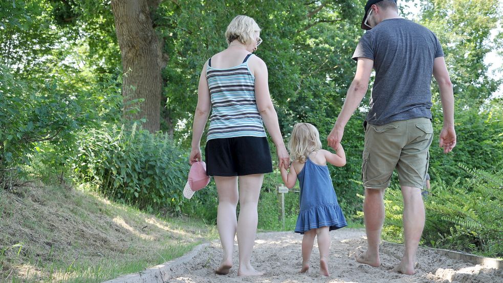 Helena (Mitte) ist begeistert vom warmen Sand unter ihren nackten Füßen. Mit Julia Engel und Torsten Heising erkundet sie zum ersten Mal den Barfußpark in Etzel. Foto: Susanne Ullrich