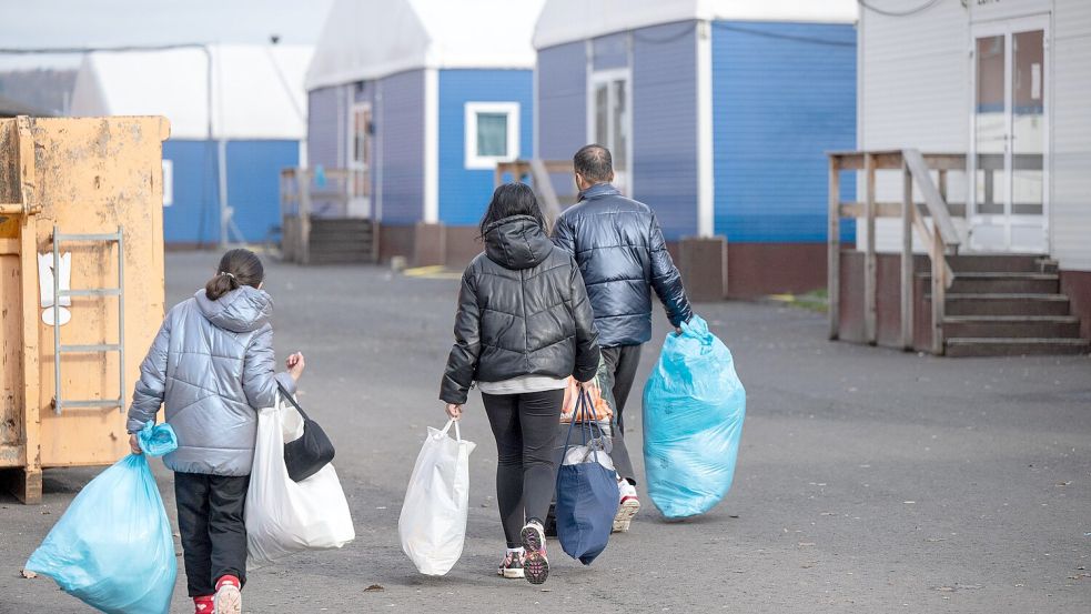 In Plastiksäcken tragen neu angekommene Flüchtlinge ihre persönlichen Habseligkeiten zu ihrer Unterkunft in einer Erstaufnahmeeinrichtung in Gießen. Vor allem für Syrer dauert das Asylverfahren inzwischen länger. Foto: BORIS ROESSLER/dpa
