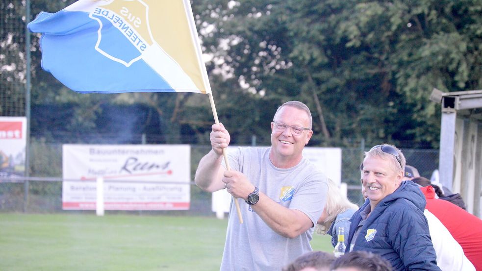 Da konnte Steenfeldes Trainer Wolfgang Behrends (links) noch lachen, als er aus Spaß während des Spiels die Vereinsfahne schwenken durfte. Später sah er dann die Rote Karte. Fotos: Weers