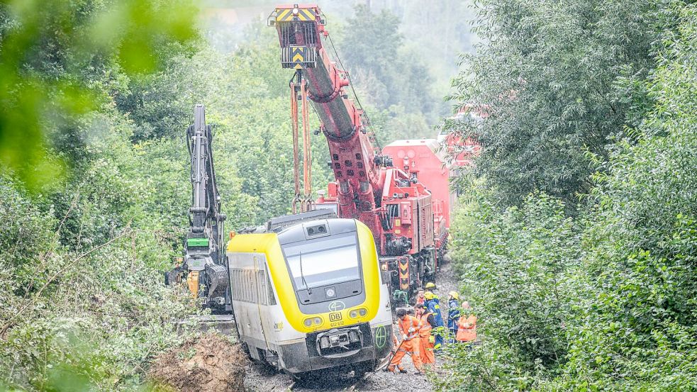 Mit einem Kran wird an der Unfallstelle, an der ein Regionalzug entgleist ist, gearbeitet. Ein Regionalexpress war am Sonntagabend (27.07.2025) in Riedlingen nach bisherigen Erkenntnissen infolge eines Hangrutsches entgleist. Foto: Jason Tschepljakow/dpa