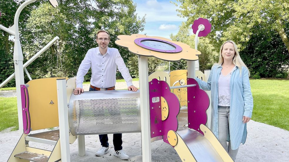 Bürgermeister Hendrik Schulz und Mitarbeiterin Ulrike Hamann präsentieren die neuen Geräte auf dem Spielplatz in der Veilchenstraße in Veenhusen. Foto: Gemeinde Moormerland