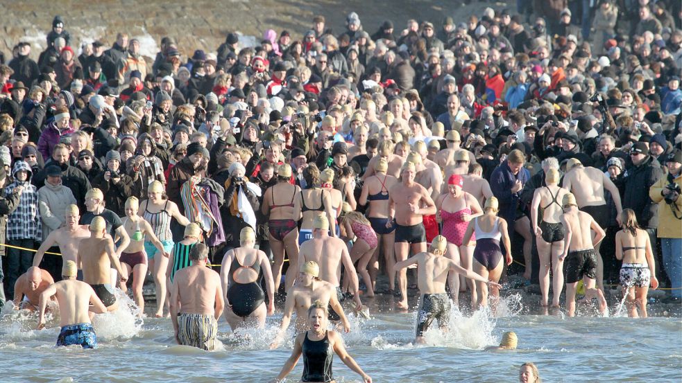 Am Neujahrsmorgen gönnen sich traditionell Hunderte von Menschen auf Norderney ein erfrischendes Bad in der Nordsee. Tausende Zuschauer feuern die Teilnehmer am Weststrand an. Foto Archiv: dpa/lno