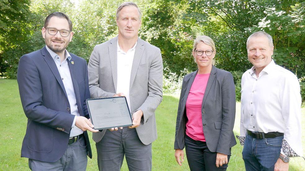 Baudezernent Eiko Ahten (links) und Judith Vogel, Leiterin des Amtes für Bauordnung, Planung und Naturschutz, vom Landkreis Aurich überreichen die digitale Baugenehmigung für die Zentralklinik an Geschäftsführer Dirk Balster (Zweiter von links) und Projektleiter Andreas Epple (rechts). Foto: Trägergesellschaft