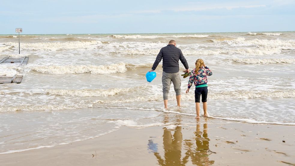 Ein typisches Urlaubsfoto aus einem x-beliebigen Familienalbum: Vater und Tochter spielen am Meer. Symboldild: IMAGO / Bihlmayerfotografie