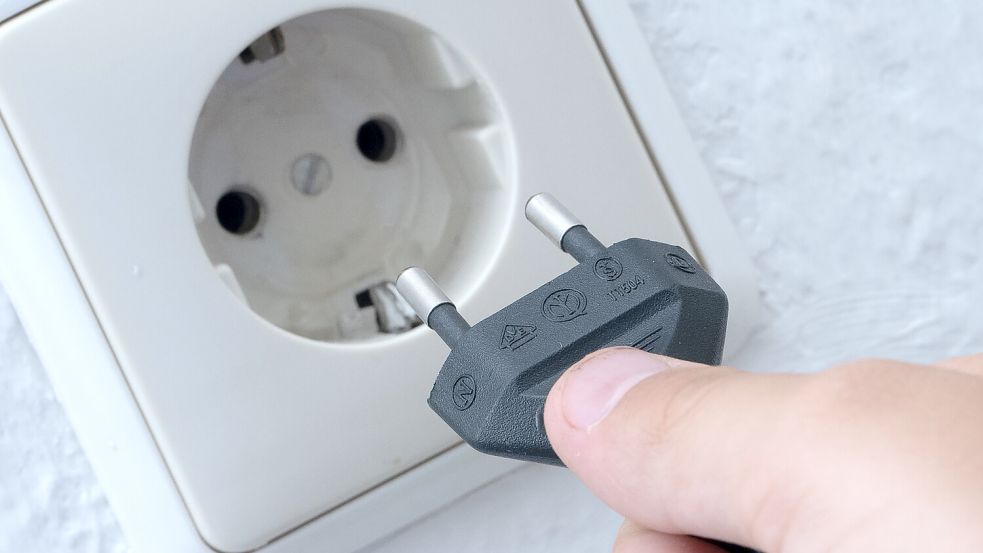Ein Mann steckt einen Stecker in eine Steckdose. Im Rheiderland hat es einen Stromausfall gegeben. Foto: Swen Pförtner/dpa