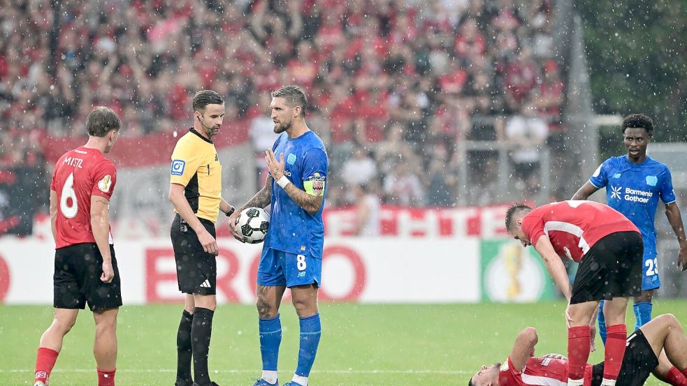 Schiedsrichter Michael Bacher (2.v.l.) muss das Spiel in Großaspach unterbrechen Foto: Bernd Weißbrod/dpa