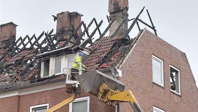 Die Dachziegel, die vom Dach der Häuserreihe in Emden fallen könnten, werden per Hand abgenommen. Foto: Mona Hanssen