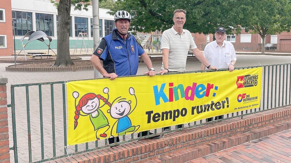 Das Foto zeigt (von links): Holger Gärtner (Polizeiinspektion Leer/Emden und Verkehrswacht Emden), Hinrich Post (Stadt Emden Fachdienst Straßenverkehr und Verkehrswacht Emden) sowie Heinz Wilhelm Weber (Verkehrswacht Emden) mit dem Banner vor der Grundschule am Wall. Foto: privat