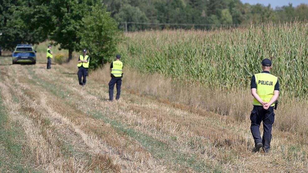 Polnische Polizisten sichern das Gebiet eines Maisfeldes in Osiny in Ostpolen, in das ein unbekanntes Flugobjekt gestürzt ist. (Foto aktuell) Foto: Wojtek Jargilo/PAP/dpa