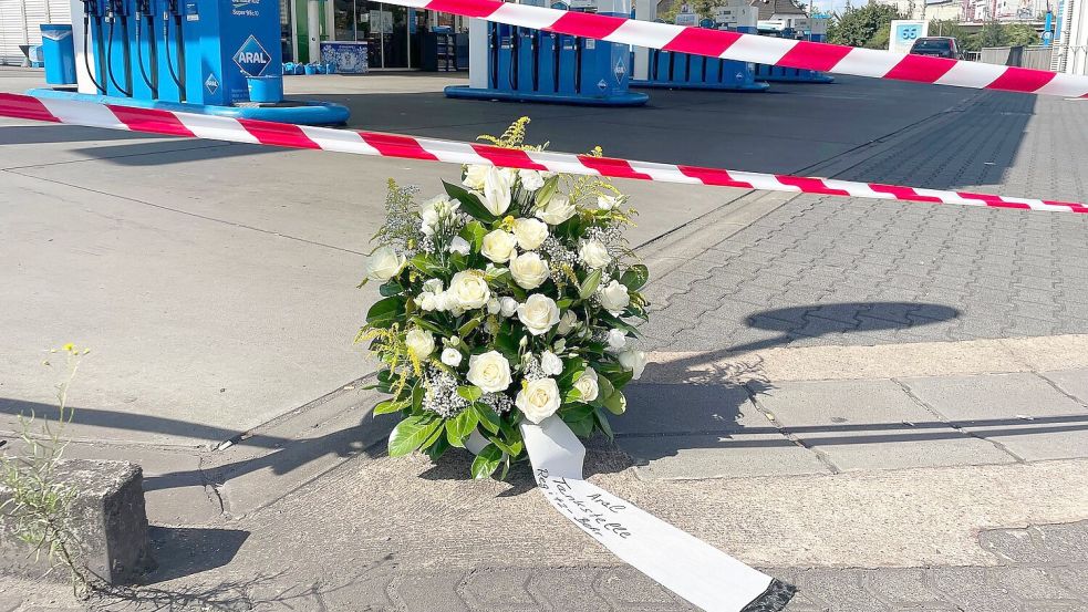 Ein großer Blumenkranz steht vor der überfallenen Tankstelle. Foto: Christian Schultz/dpa