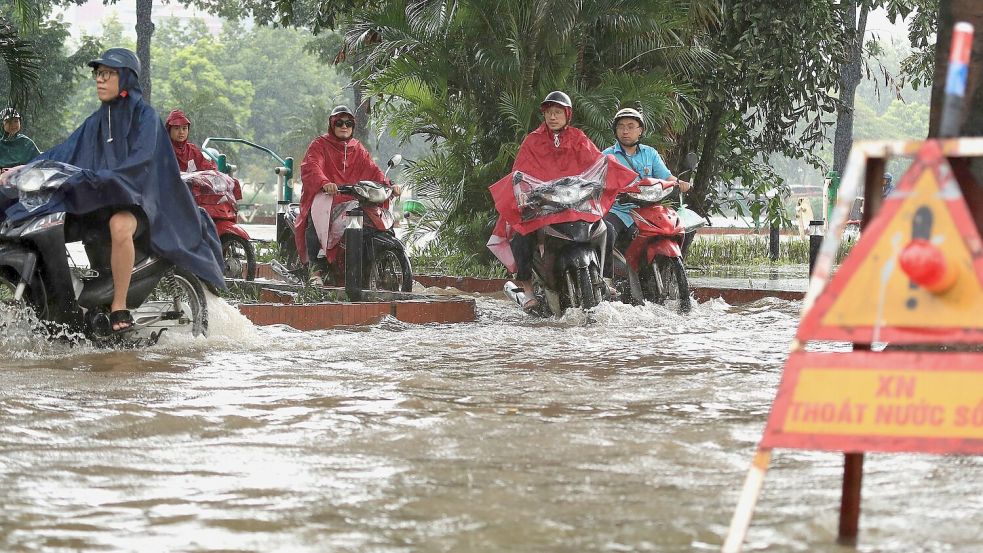 In Hanoi bahnten sich viele Motorradfahrer ihren Weg durch die Wassermassen. Foto: Huy Han/AP/dpa