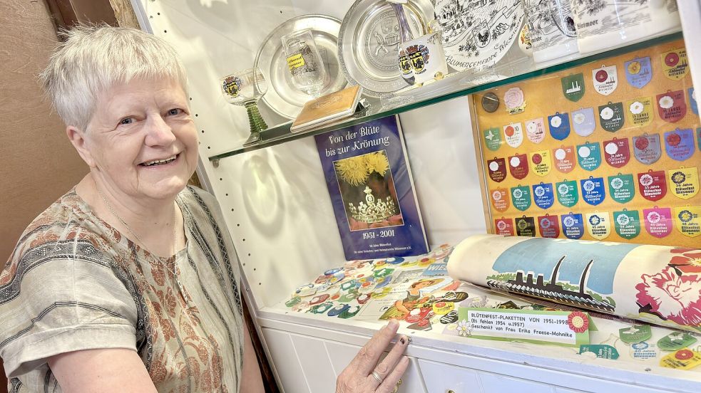 Arianne Schoon vom Wiesmoorer Torf- und Siedlungsmuseum vor einer Vitrine mit einer ganz besonderen Sammlung: Zu sehen sind Blütenfest-Plaketten. Foto: Klaus Ortgies