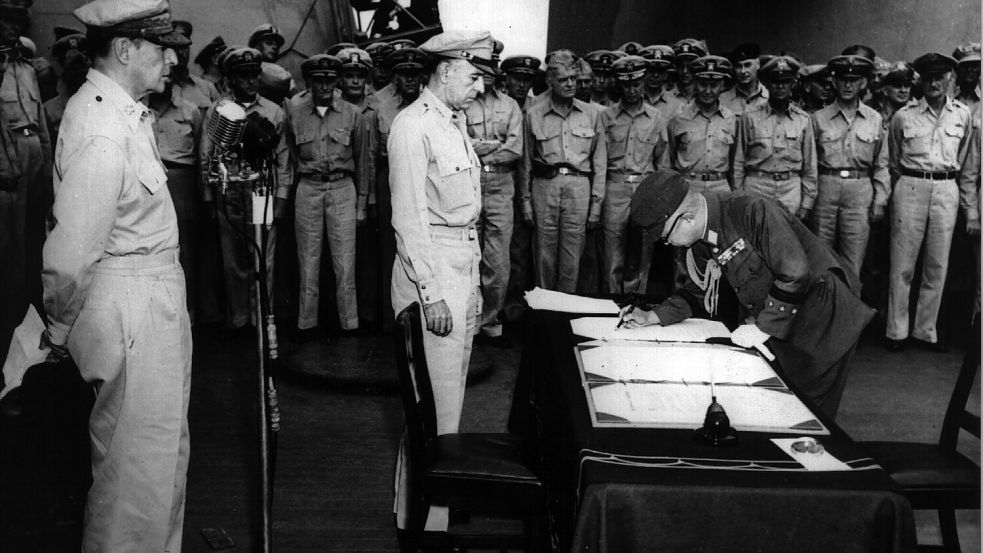 Das endgültige Ende des Zweiten Weltkriegs: General Yoshijiro Umezu unterzeichnet die Kapitulationsurkunde an Bord der „USS Missouri“. Links im Bild der US-Oberbefehlshaber Douglas MacArthur. Foto: dpa/DB