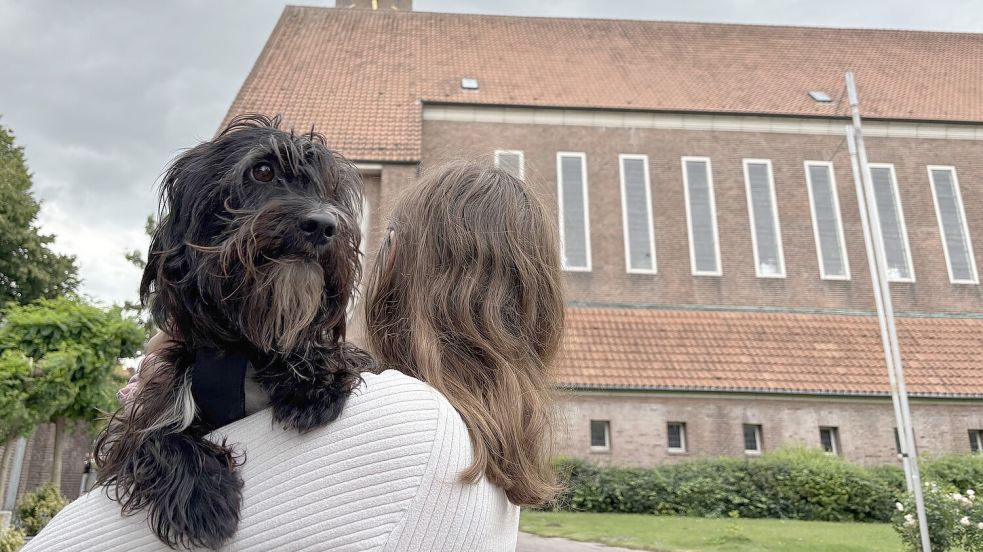 Hundemädchen Frieda dürfte jetzt in Emden mit zu einem Gottesdienst der Martin-Luther-Gemeinde. Die Kirche an der Bollwerkstraße ist im Hintergrund zu sehen. Der Gottesdienst am 14. September wird aber auf einer Wiese am Gemeindehaus Conrebbi abgehalten. Foto: Mona Hanssen