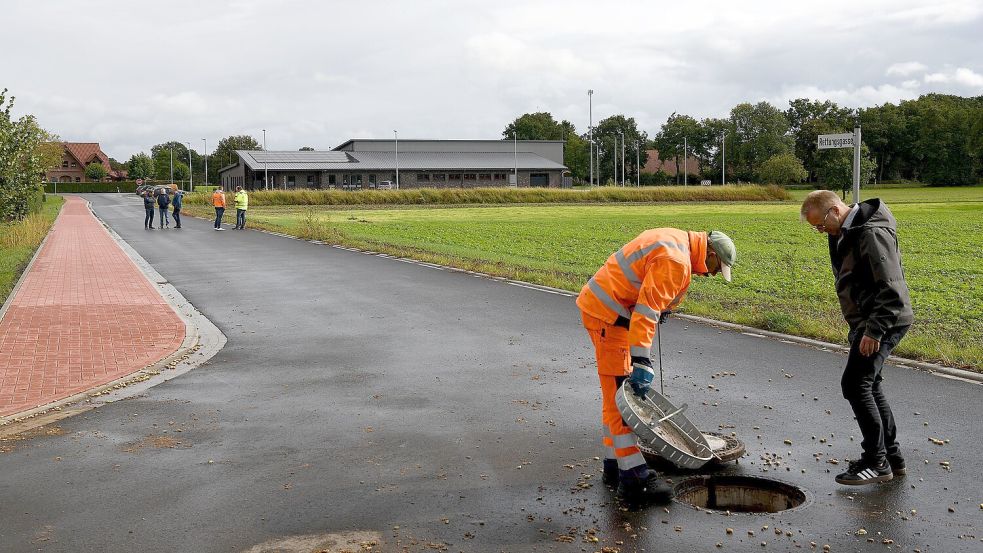 Unter dem Deckel ist alles okay. Vom ordnungsgemäßen Zustand der Rettungsgasse und der darunterliegenden Kanalisation überzeugten sich Vertreter der Gemeinde Uplengen, des Gemeinderates und der ausführenden Baufirma bei der offiziellen Abnahme. Foto: Stromann