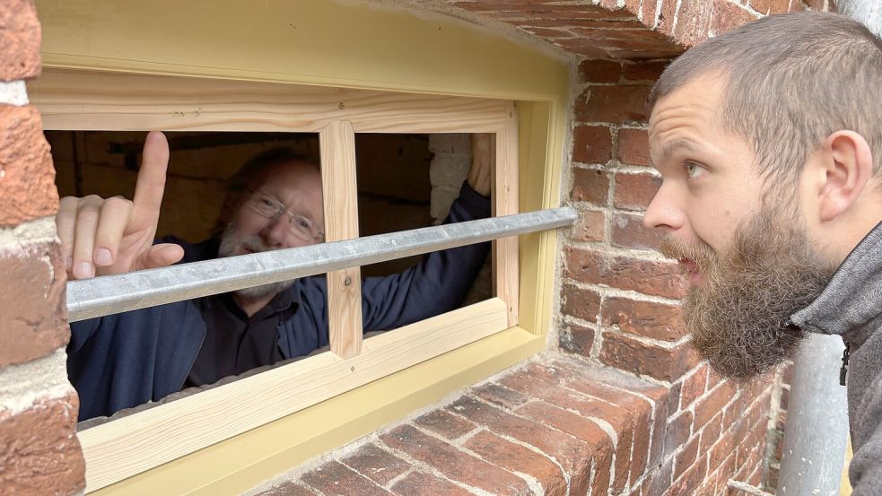 Holger Rodiek (links) und Schreiner Jonas Kinast nehmen letzte Änderungen an einem Kellerfenster vor. Hier sollen Fliegengitter eingebaut werden, damit der Keller im Winter besser belüftet werden kann. Wenn alles stimmt, wird der Rahmen wie bei den anderen Fenstern grau lackiert. Foto: Hannah Weiden