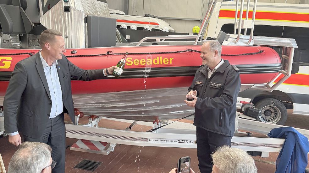 Landrat Holger Heymann (links) tauft das neue Motorrettungsboot im Beisein des Wittmunder DLRG-Vorsitzenden Hendrik Schultz (rechts) auf den Namen „Seeadler“. Foto: privat