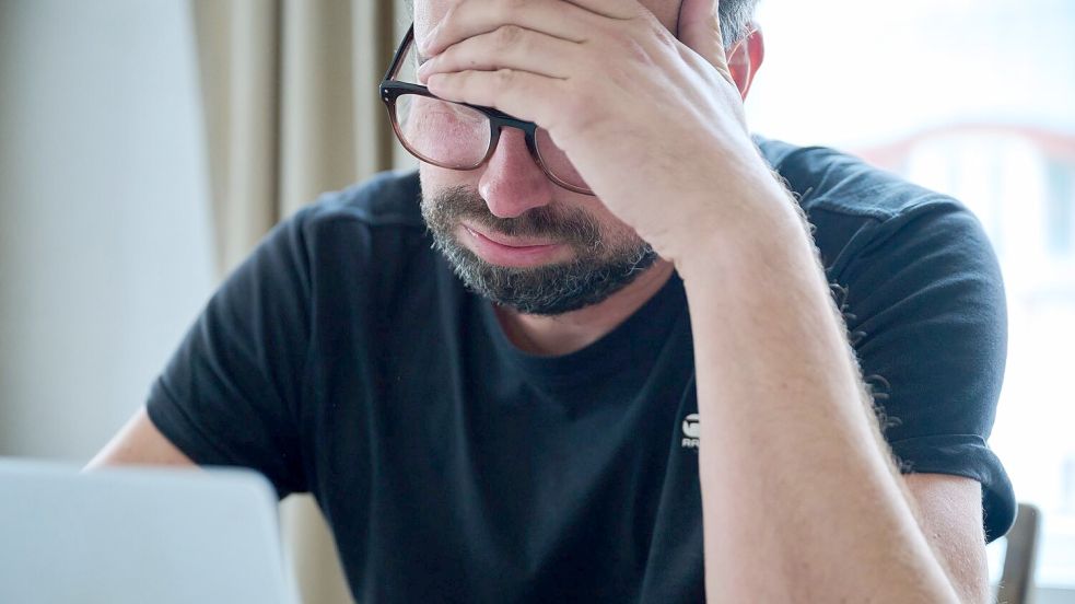 Ein Mann sitzt vor einem Laptop und seufzt. Foto: Annette Riedl