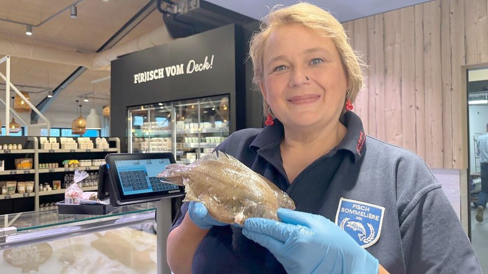 Anke Neujahr hinter dem Tresen der Fischereigenossenschaft, in den Händen Kliesche. Foto: Imke Oltmanns