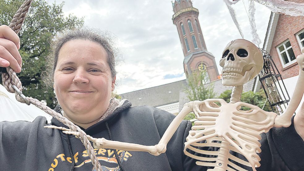 Melanie Amthor mit einem der Skelette, die den Garten des ehemaligen Pastorenhauses zieren. Foto: Marion Janßen