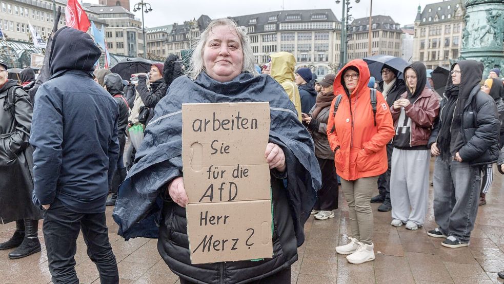 Eine Demonstrantin in Hamburg stellt auf einem Pappschild eine Frage an Bundeskanzler Friedrich Merz (CDU). Foto: Markus Scholz