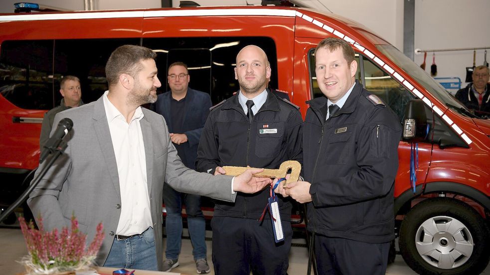 Samtgemeindebürgermeister Christoph Busboom (links) überreicht Ortsbrandmeister Thomas Rademacher (rechts) und dessen Stellvertreter Marco Martens den symbolischen Schlüssel zum neuen Gerätehaus. Foto: Melchert Stromann