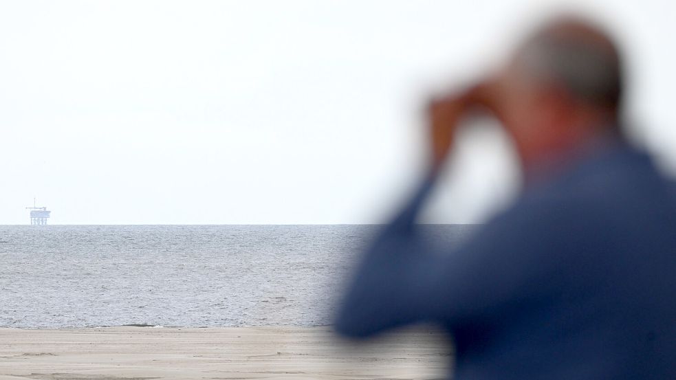 Ein Urlauber blickt von Borkum aus auf die Gasplattform NO5-A des Unternehmens One-Dyas. Foto: Lars Penning/dpa