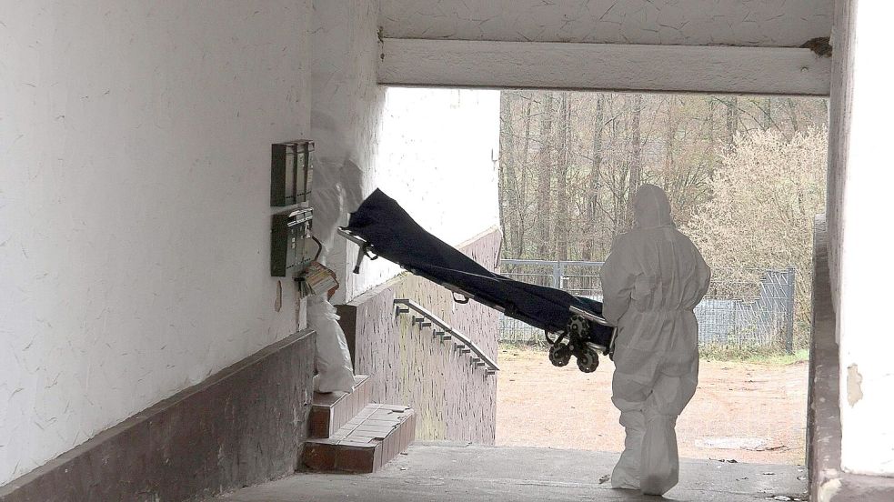 Beamte der Spurensicherung bringen eine Trage in ein Wohnhaus. Foto: Thorsten Kremers
