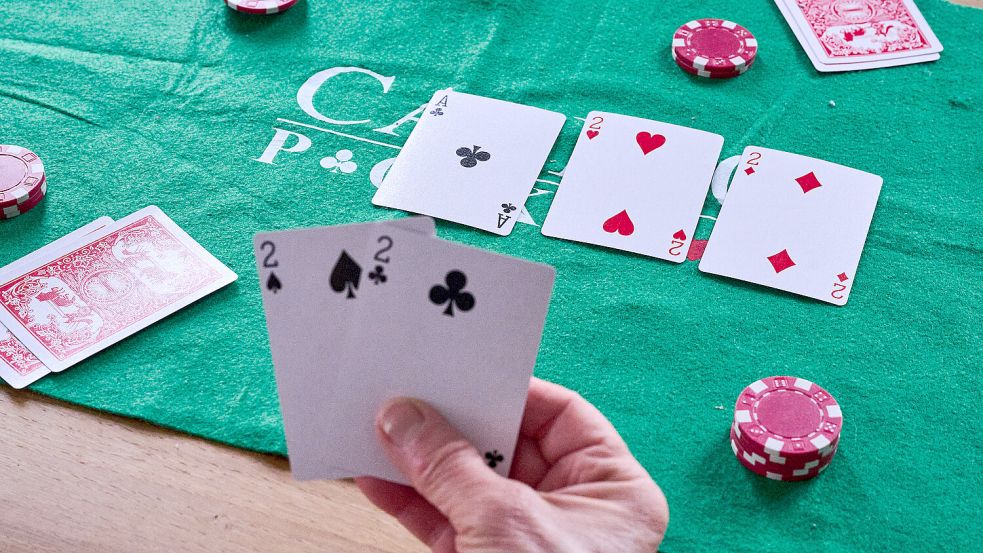 Eine Person hält in einer gestellte Szene beim Pokern zwei Zweier in der Hand. Foto: DPA