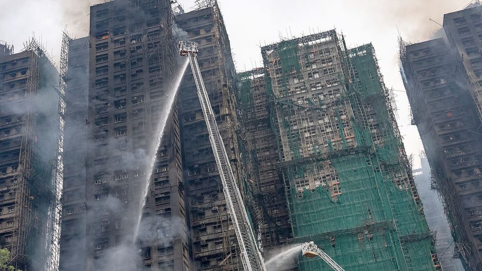 Auch fast 20 Stunden nach Ausbruch des Feuers kämpften die Einsatzkräfte noch gegen Flammen. Foto: Chan Long Hei/AP/dpa