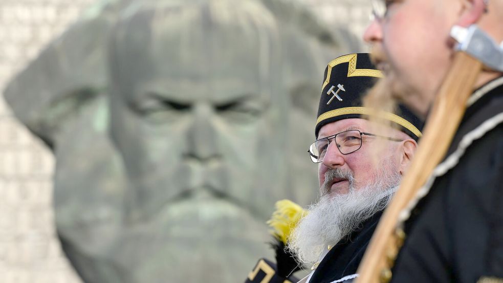 Zum Abschluss des Kulturhauptstadtjahres in Chemnitz ziehen Teilnehmer der Bergparade im traditionellen Habit am Karl-Marx-Monument vorbei. Foto: Hendrik Schmidt