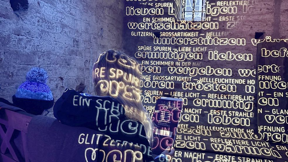 In weißer Schrift werden verschiedene Worte auf die alte Mauer projiziert. Greta und Hannes Bikker sind von dem Projekt begeistert. Foto: Lasse Paulsen