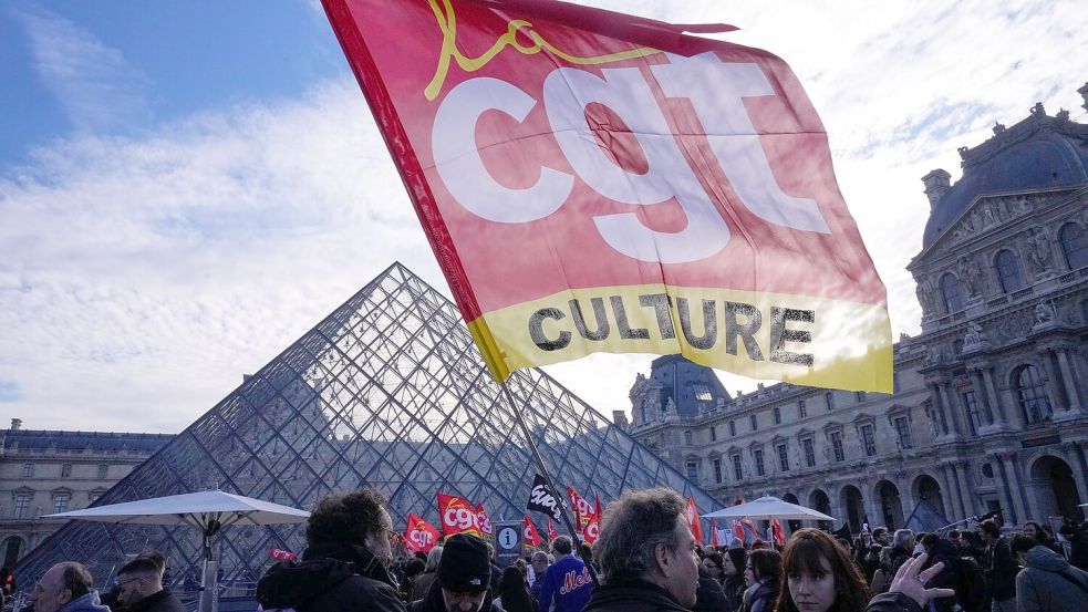 Angestellte zeigen eine Flagge der Gewerkschaft CGT vor dem Louvre, nachdem sie für einen Streik gestimmt haben. Foto: Michel Euler/AP/dpa