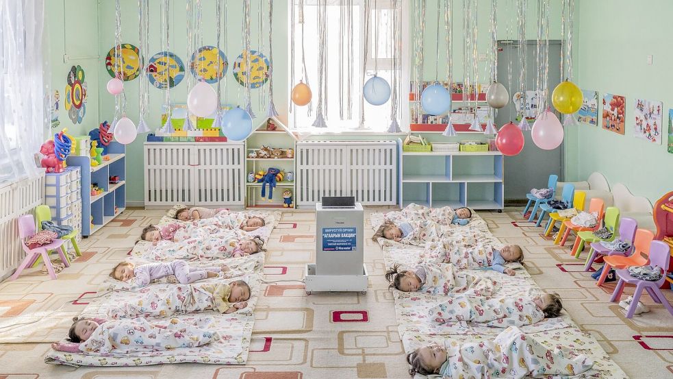 In einem Kindergarten in Ulaanbaatar, der Hauptstadt der Mongolei, liegen Kinder auf dem Boden um einen aufgestellten Luftfilter herum, der die Schadstoffkonzentration senken soll. Foto: Natalya Saprunova/Unicef/dpa