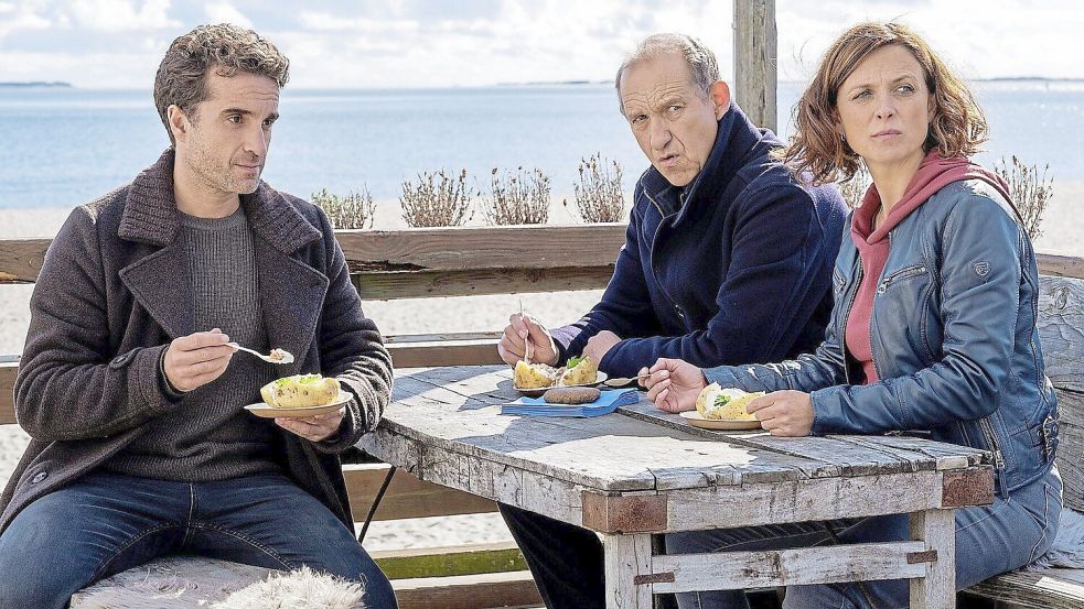 Oliver Wnuk (links) in einer Szene mit seinen „Nord Nord Mord“-Kollegen Julia Brendler und Peter Heinrich Brix. Die Kommissare sitzen beim Mittagessen zusammen und beraten über den Stand der Ermittlungen. Foto: ZDF/Manju Sawhney