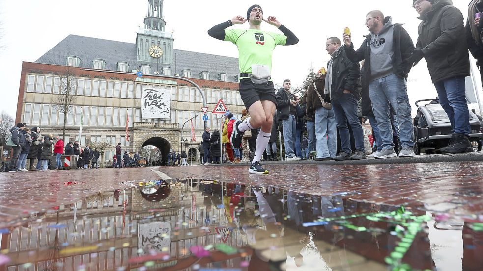 Auf der Strecke des Silvesterlaufs bildeten sich teilweise Pfützen – in dieser vor dem Emder Rathaus landete auch Konfetti. Foto: Jens Doden, Emden
