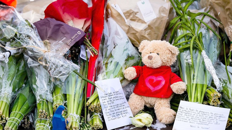 Menschen legen Blumen, Teddys und Botschaften am Brandort ab. Foto: Jean-Christophe Bott