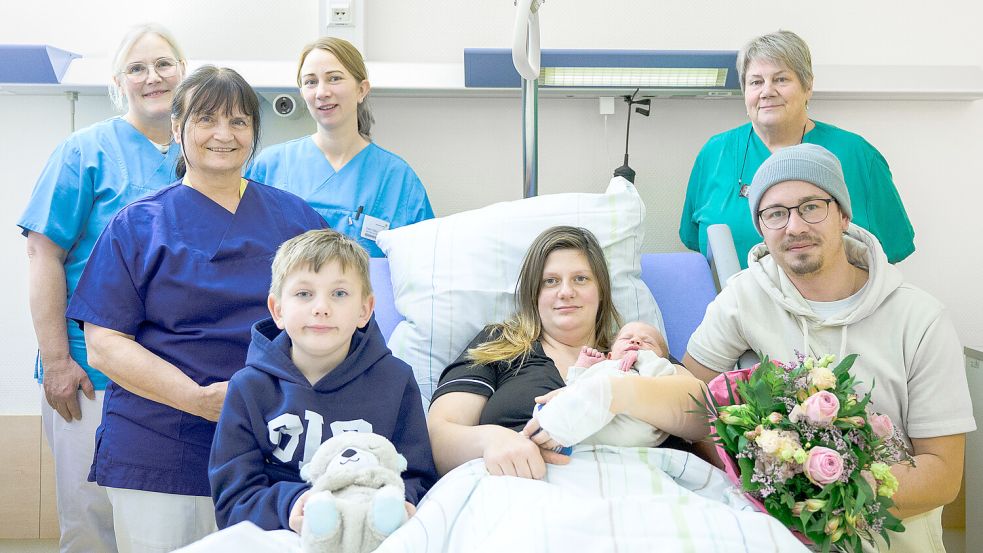 Das Foto zeigt Mutter Laura Bredehorn mit Neujahrsbaby Louis auf dem Arm (Mitte), gemeinsam mit Mann Marc-Kevin und Bruder Elias und dem Team der Geburtshilfe und der Wochenstation am Borro. Foto: Borromäus-Hospital Leer