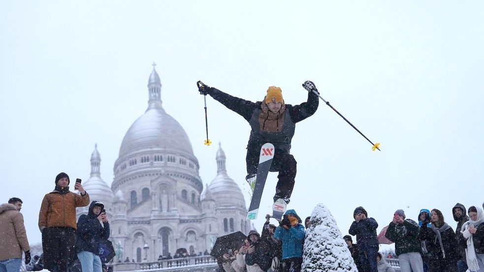 Ein Mann springt mit seinen Skiern den Hügel bei der Basilika Sacre-Coeur im französischen Paris hinunter. Foto: Aurelien Morissard/AP/dpa