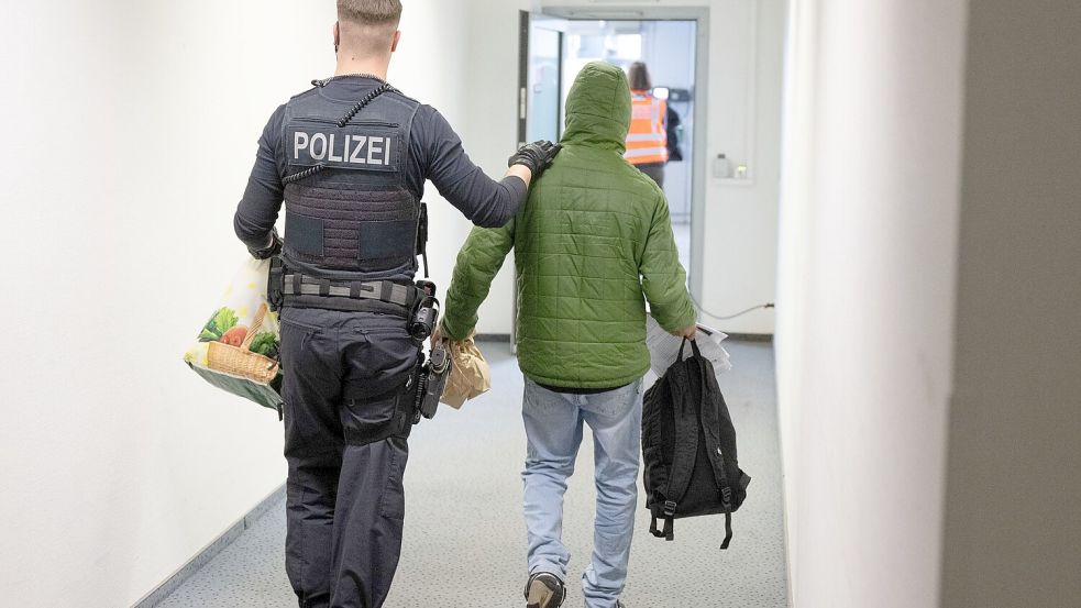 Ein Polizeibeamter bringt einen Mann zu einem Abschiebeflug nach Pakistan. (Archivfoto) Foto: Boris Roessler