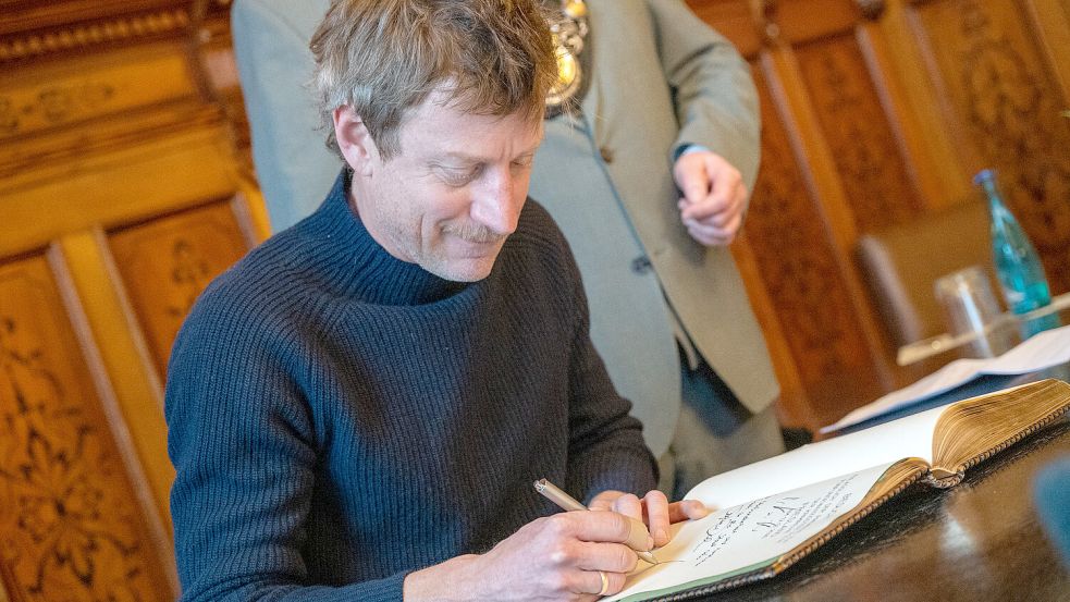 Maxim Mehmet alias Henk Cassens trägt sich ins goldene Buch ein. Foto: Klaus Ortgies