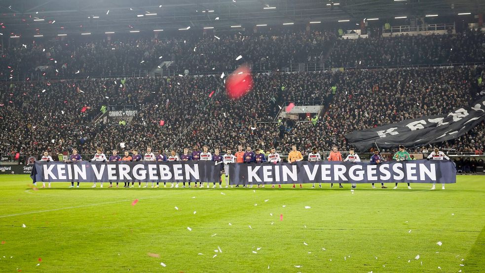 Spieler beider Teams halten vor Spielbeginn ein Banner anlässlich das Holocaust-Gedenktags hoch. Foto: Christian Charisius