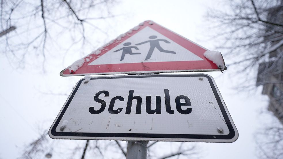 Schnee liegt auf einem Verkehrsschild und Hinweisschild mit der Aufschrift „Schule“. Foto: DPA