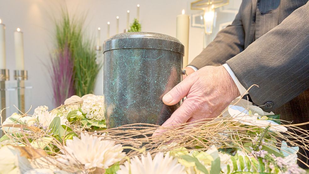 Ein Bestatter platziert eine Urne. Foto: Thomas Frey/dpa