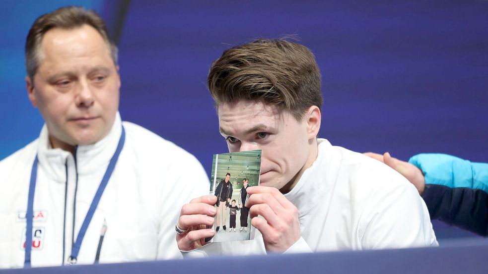 Maxim Naumov hielt nach seinem Auftritt ein Bild in die Kamera, das ihn als Dreijährigen mit seinen Eltern zeigt. Foto: Li Ming/XinHua/dpa