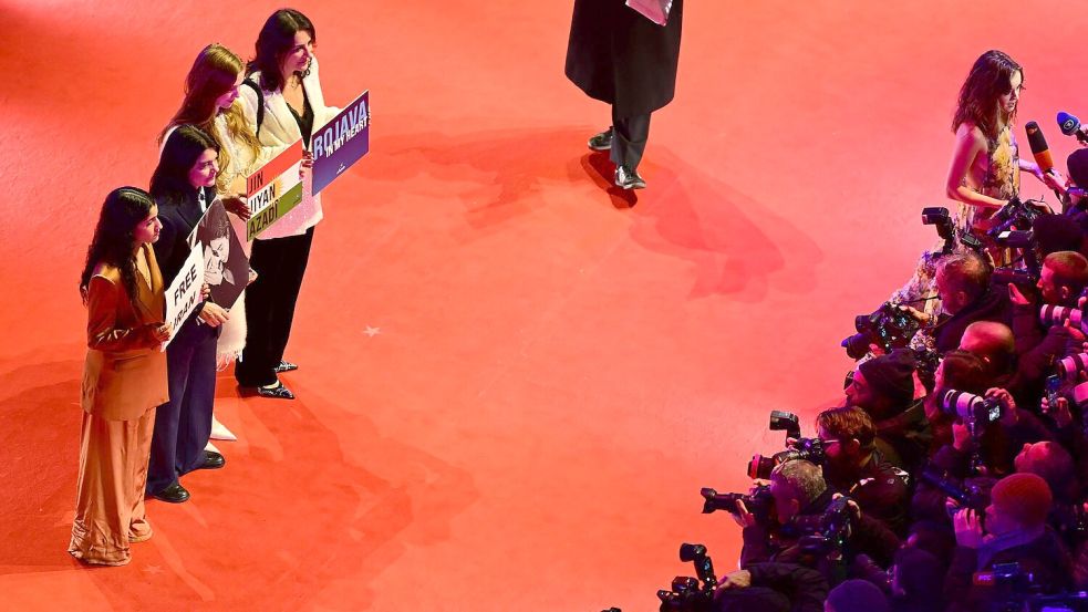 Gäste, darunter die deutsch-iranische Schauspielerin Jasmin Tabatabai (2. v. l.), halten Protestschilder hoch. Foto: Sebastian Christoph Gollnow